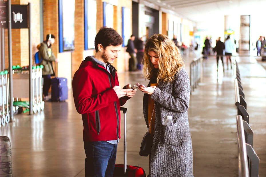 People Using Mobile Phones At An Airport